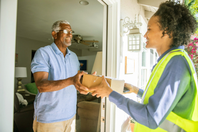 delivery woman handing man a package