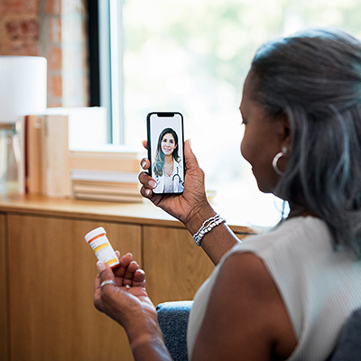 A lady looking at her smart phone on a video telehealth call with a nurse