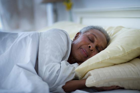 A senior sleeps in a bed