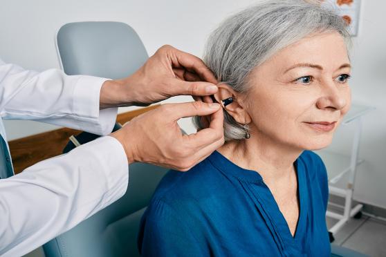 A senior gets fitted for a hearing aid
