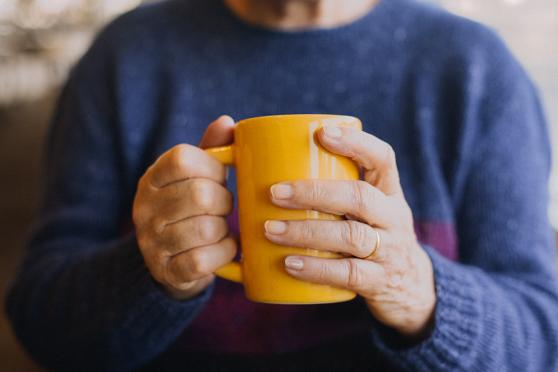 A person in a blue sweater holds a yellow mug