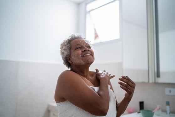 A senior applies lotion in a bathroom