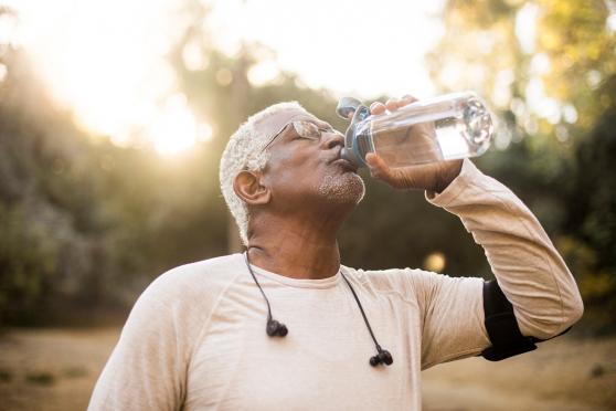 a senior man drinks water out of a bottle