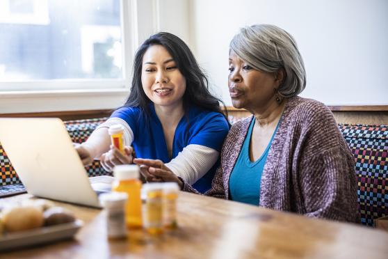 A health aide helps a senior with medication management