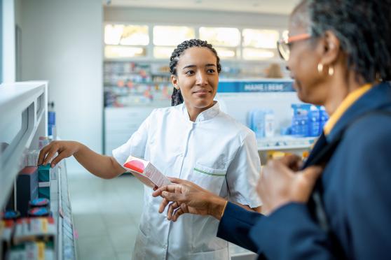 A pharmacist helps a senior find medicine