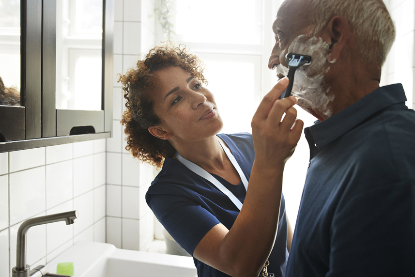 Caregiver helping man shave 