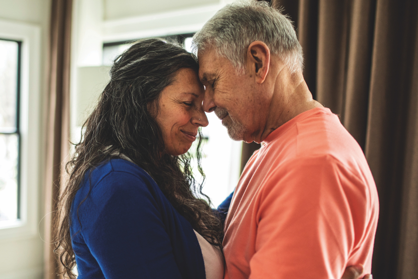 A man and woman standing with their foreheads touching.