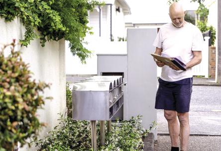 An older man standing by his mailbox