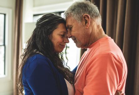 A man and woman standing with their foreheads touching.