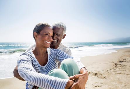 An older black couple sitting on the beach