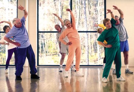 A group of seniors stretches in a fitness class