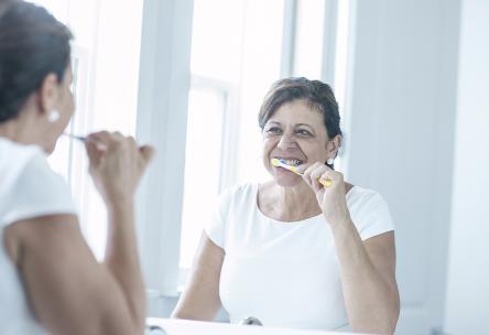 An older woman brushing her teeth