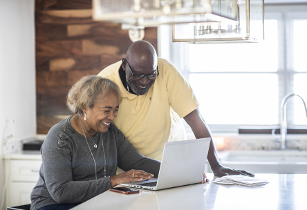 An older black couples looks at a laptop