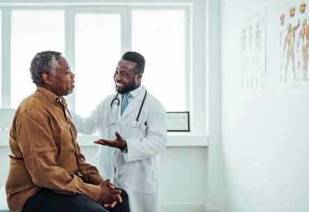 An elder black man talks to a black doctor