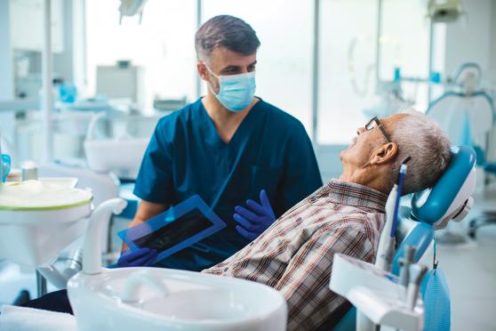 A dentist talking to a patient sitting in a dental chair