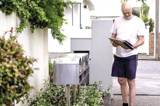 An older man standing by his mailbox