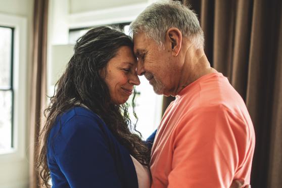 A man and woman standing with their foreheads touching.