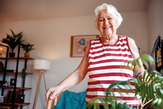 A woman smiling and holding a cane.