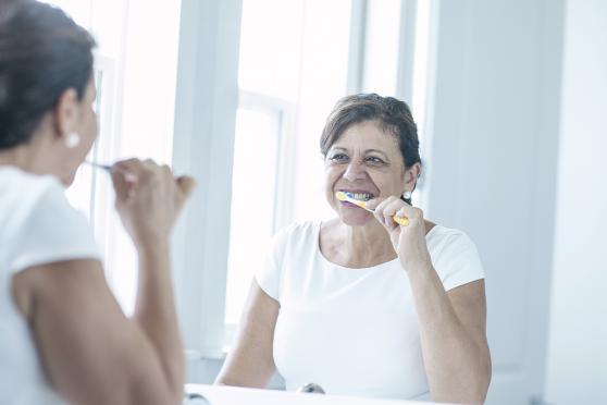 An older woman brushing her teeth