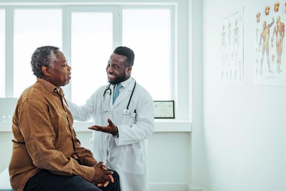 An elder black man talks to a black doctor