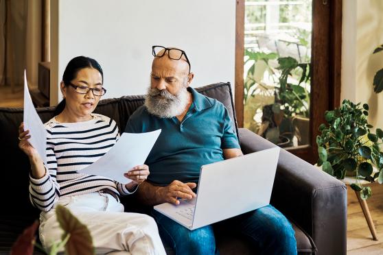 Man and woman looking at papers and laptop at home