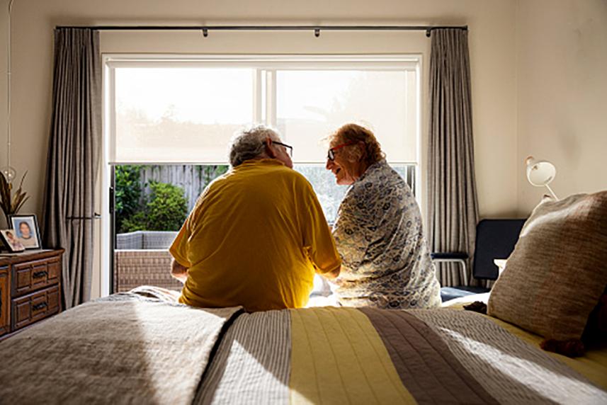 A couple sitting on a bed.