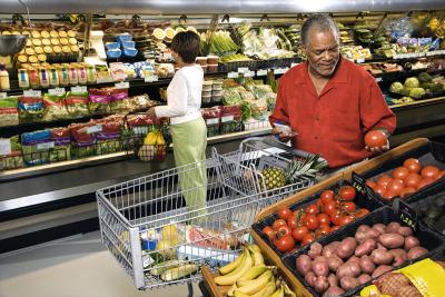 An older couple grocery shopping in the produce section