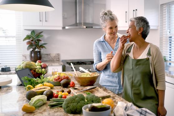 Dos mujeres en una cocina con comida sobre la encimera.
