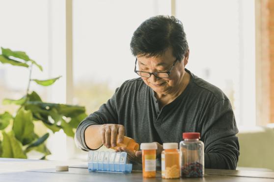 Man putting medications in pill organizer